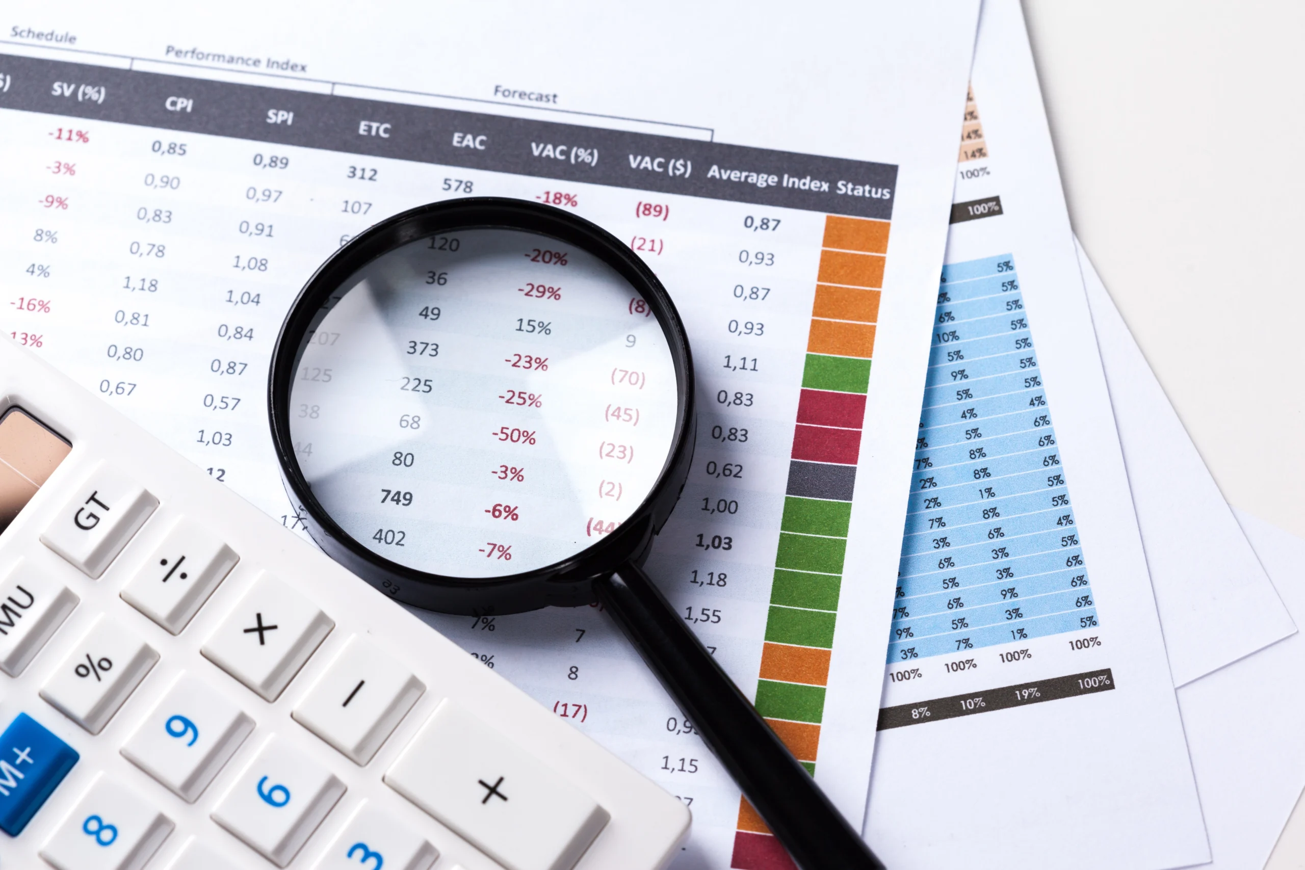 Une loupe posée sur des fiches de paie avec une calculatrice à côté, illustrant l’audit et la vérification des bulletins de paie pour assurer la conformité et l’exactitude des salaires en entreprise