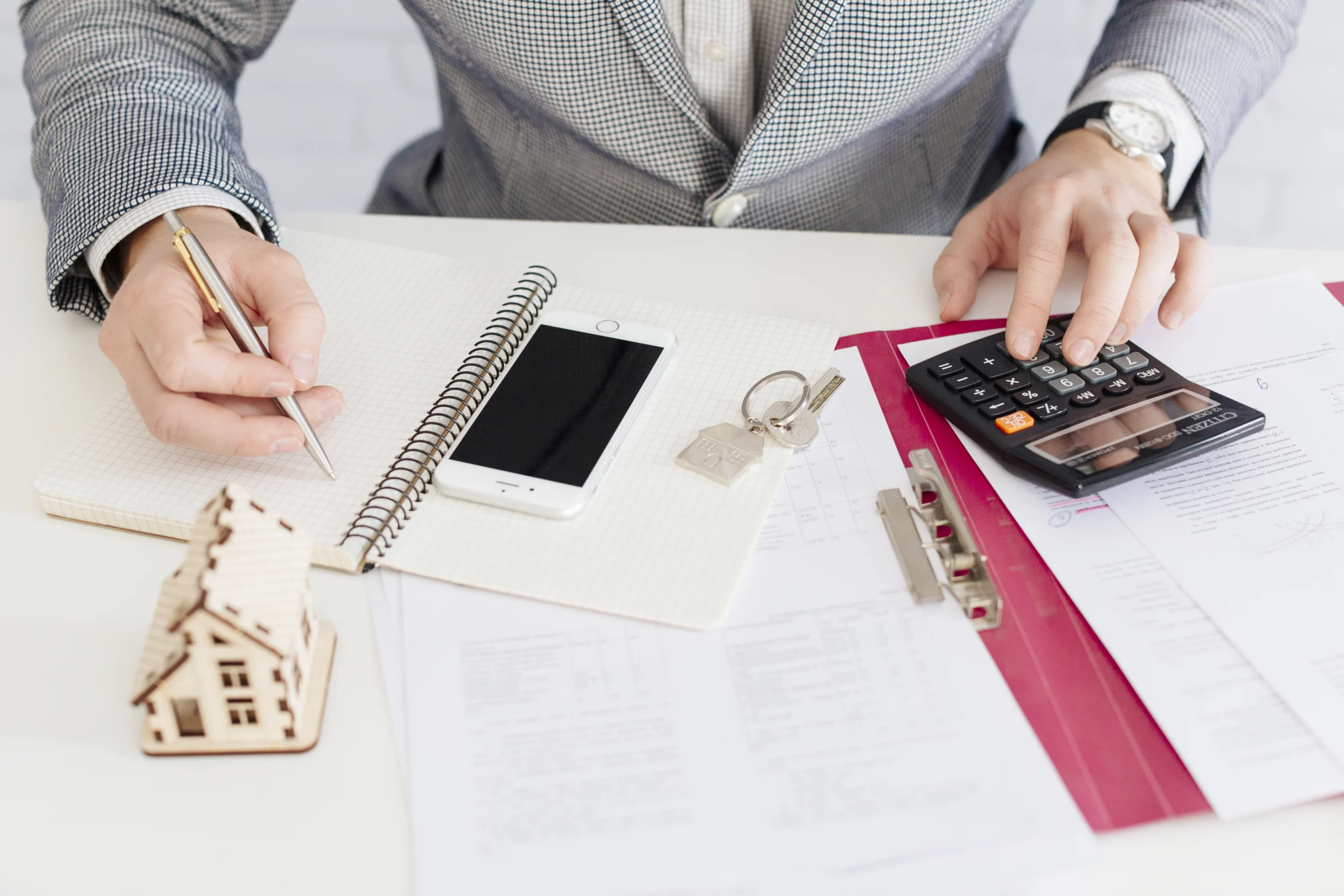 Un particulier assis à son bureau, concentré sur ses calculs pour l'optimisation fiscale personnelle. Des documents financiers, une calculatrice et un ordinateur portable sont visibles sur le bureau, montrant le processus de gestion et de planification fiscale. L'environnement est calme et professionnel, mettant en avant l'attention portée aux détails et à l'amélioration des finances personnelles.